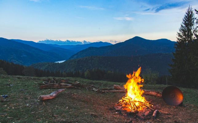 Cozy campfire against a mountain backdrop at twilight in Valea Drăganului, Romania.